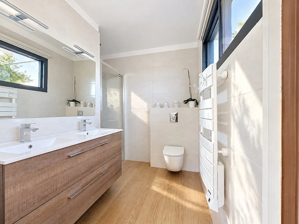 Salle de bains lumineuse avec baignoire et meuble en bois